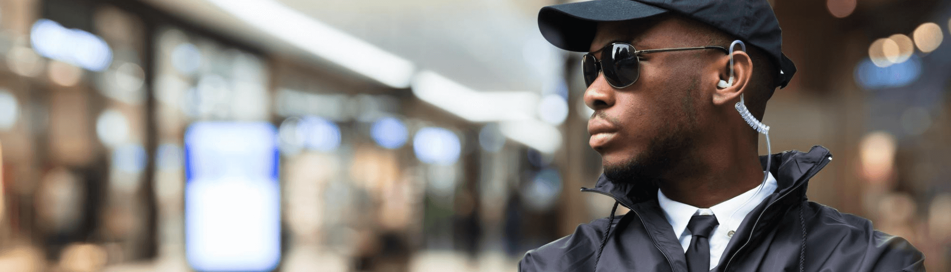 security guard in windbreaker wearing a baseball cap and sunglasses